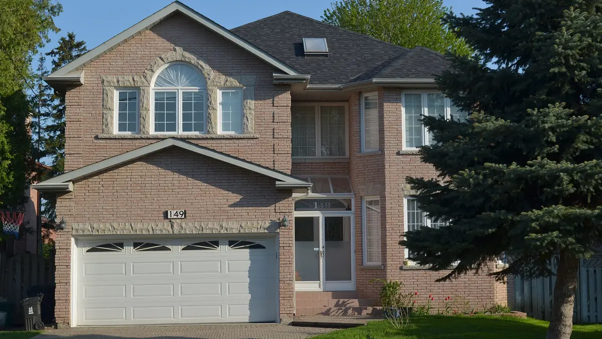 Two-storey brick house with an attached double garage and a spruce tree
