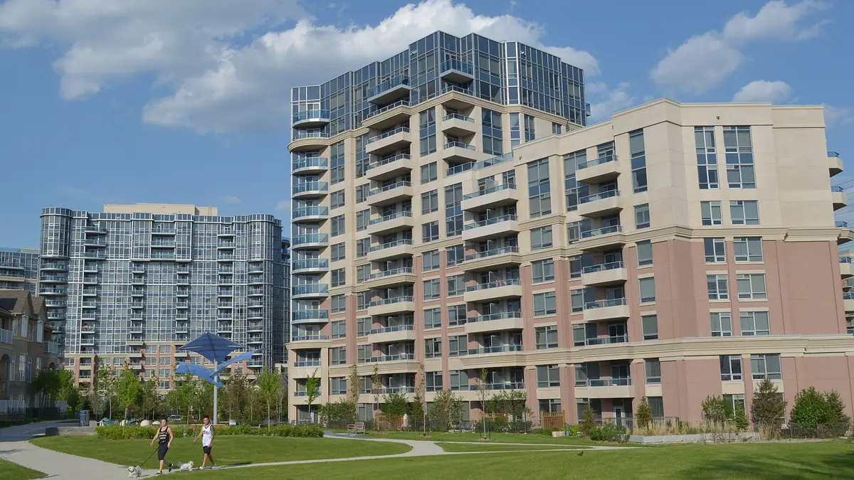 Mid-rise condominium buildings with balconies overlooking a landscaped park