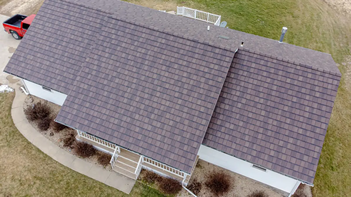 Shingled roof of a white bungalow seen from above, with porch steps and lawn