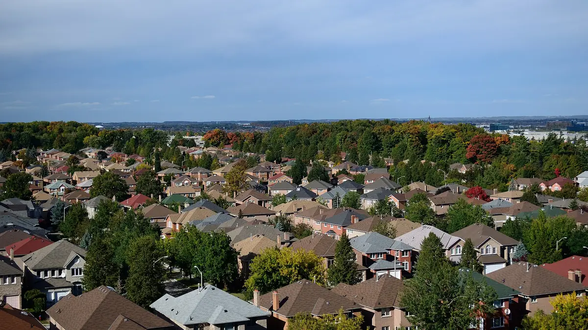 Rooftops of a suburban neighbourhood surrounded by trees in early autumn colour