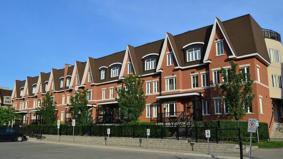 Row of red brick townhouses with peaked gables under a clear blue sky