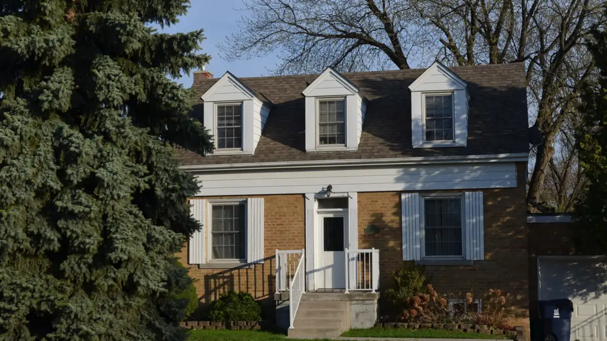 Brick storey-and-a-half house with three dormer windows and a white front door