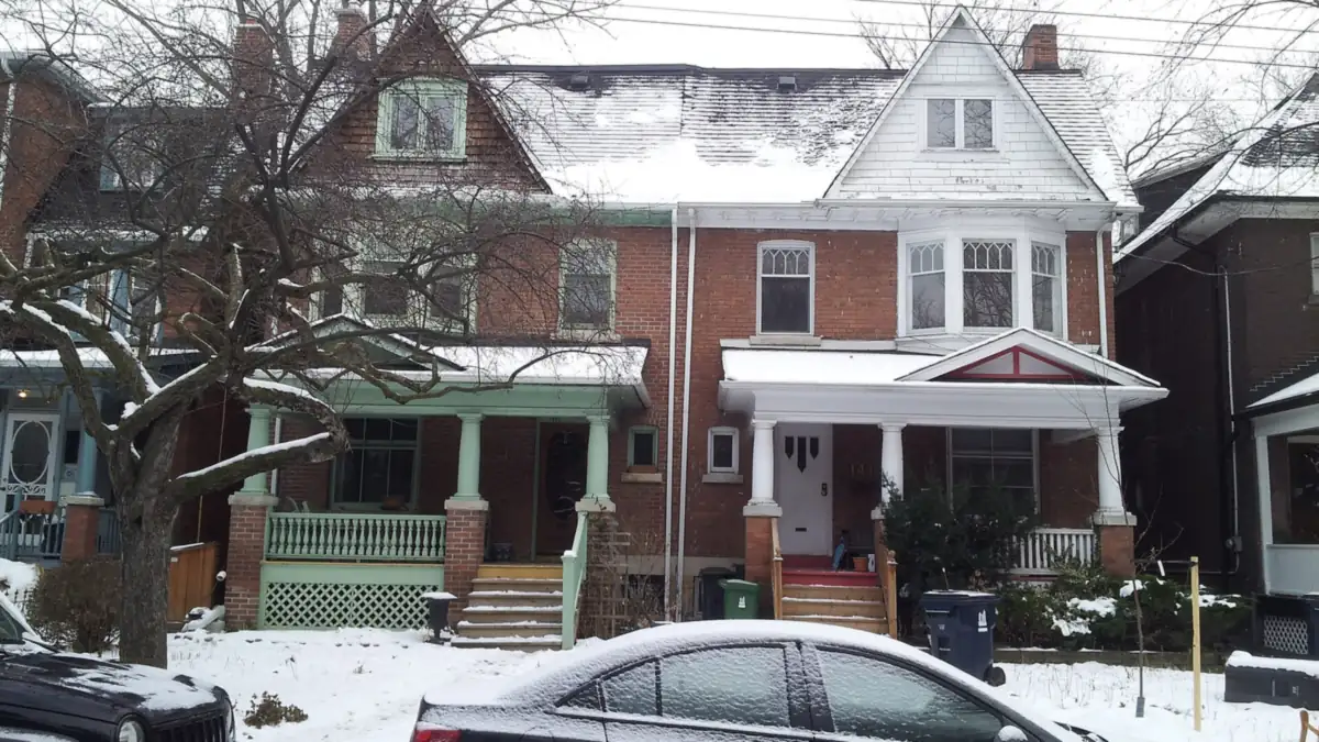 Pair of brick semi-detached houses with covered porches after a light snowfall