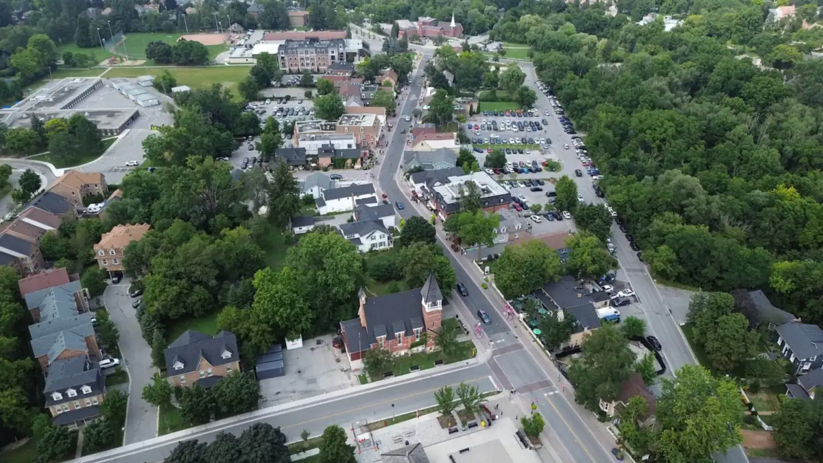 Aerial view of a small town main street with a brick church and tree-lined lots