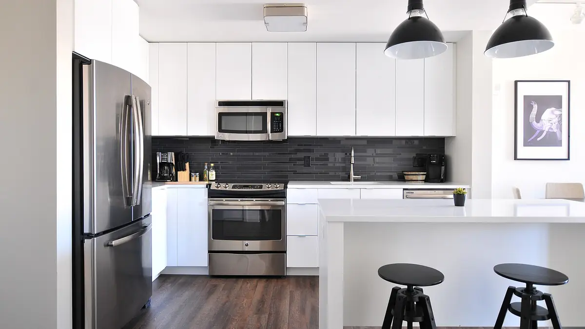 Modern kitchen with white cabinets, stainless steel appliances and a white island